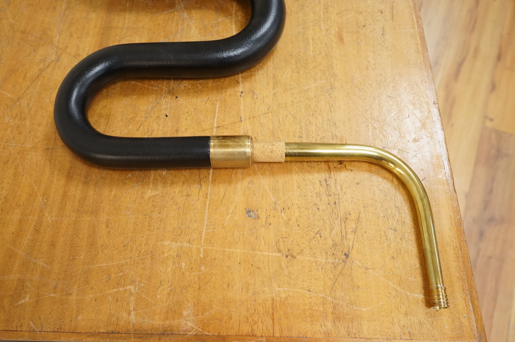 A black painted serpent open hole wind musical instrument, with brass neck (missing mouthpiece).